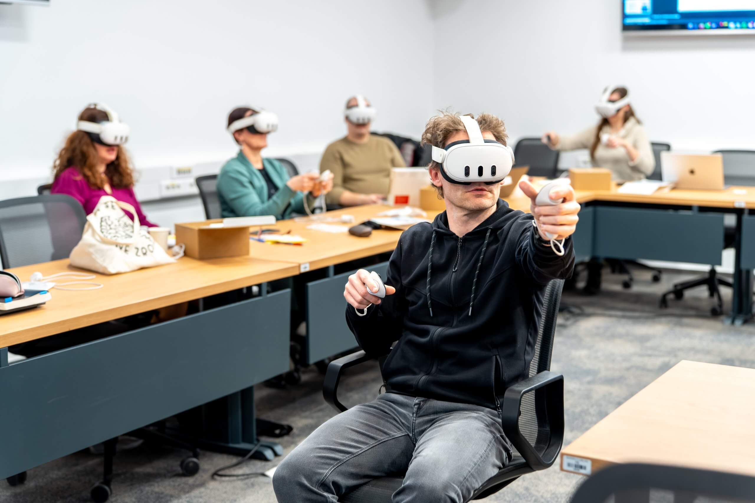 Predavatelj razlaga delovanje aplkiacije uporabniku, ki ima na glavi virtualna očala in v rokah krmilnike.